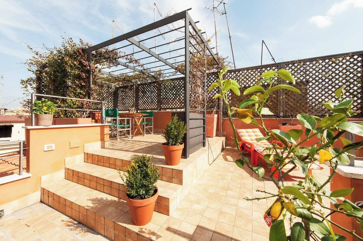 Eine Dachterrasse mit Pergola, Topfpflanzen und Gartenmöbeln.