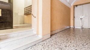 A hallway with marble steps, a metal staircase, and a white door.