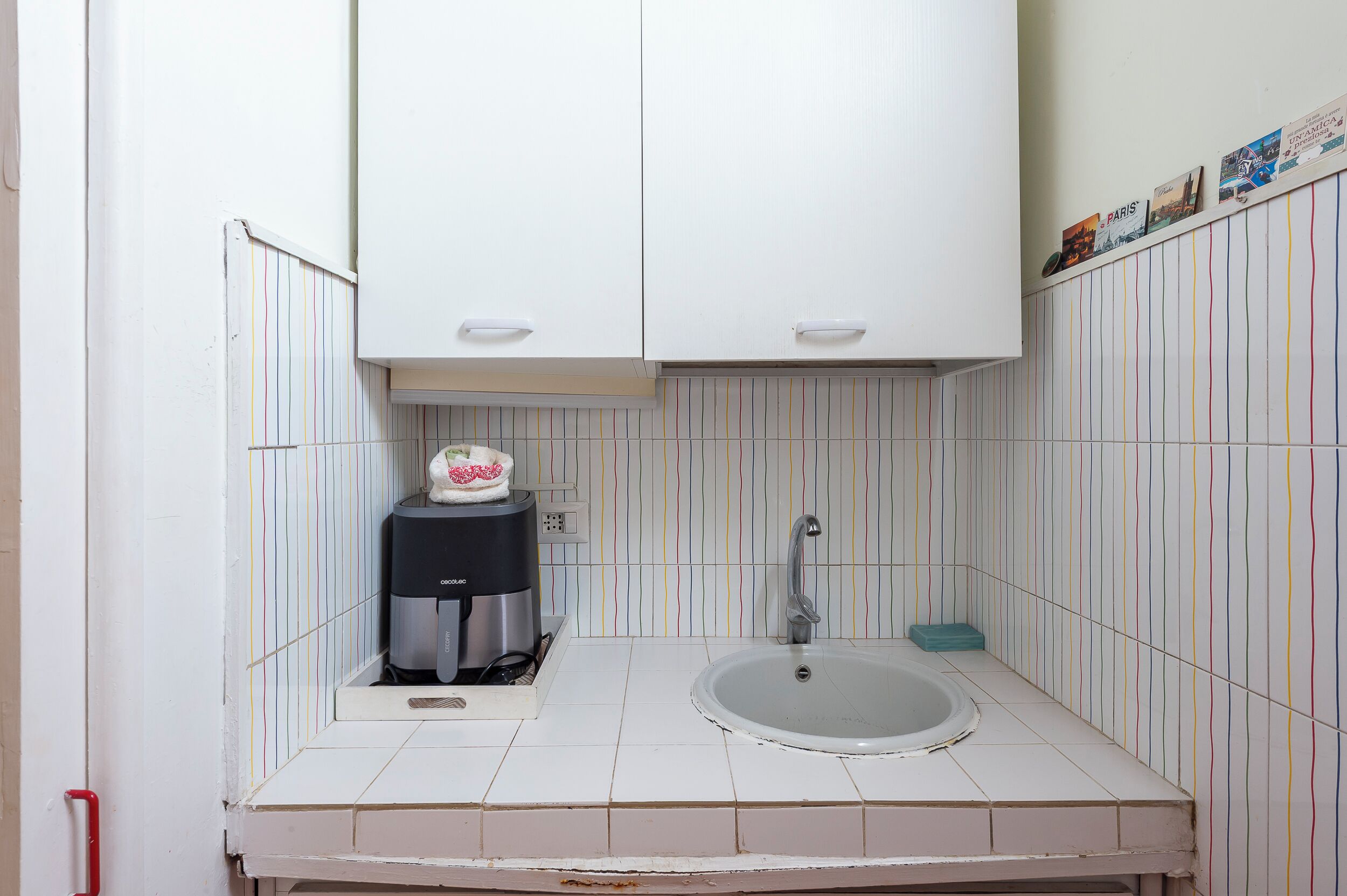 A small kitchen with white cabinets, a coffee maker, and a sink.