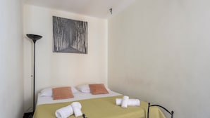 Une chambre d’hôtel avec un lit, une lampe sur pied et un tableau au mur.
