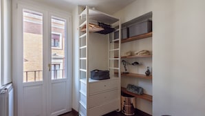Un dressing avec des portes ouvertes, des étagères et des tiroirs.