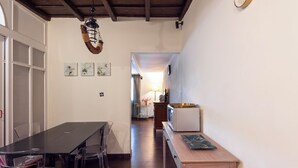 Un espace repas comprenant une longue table, des chaises et une petite table d’appoint en bois sur laquelle se trouve un bol.