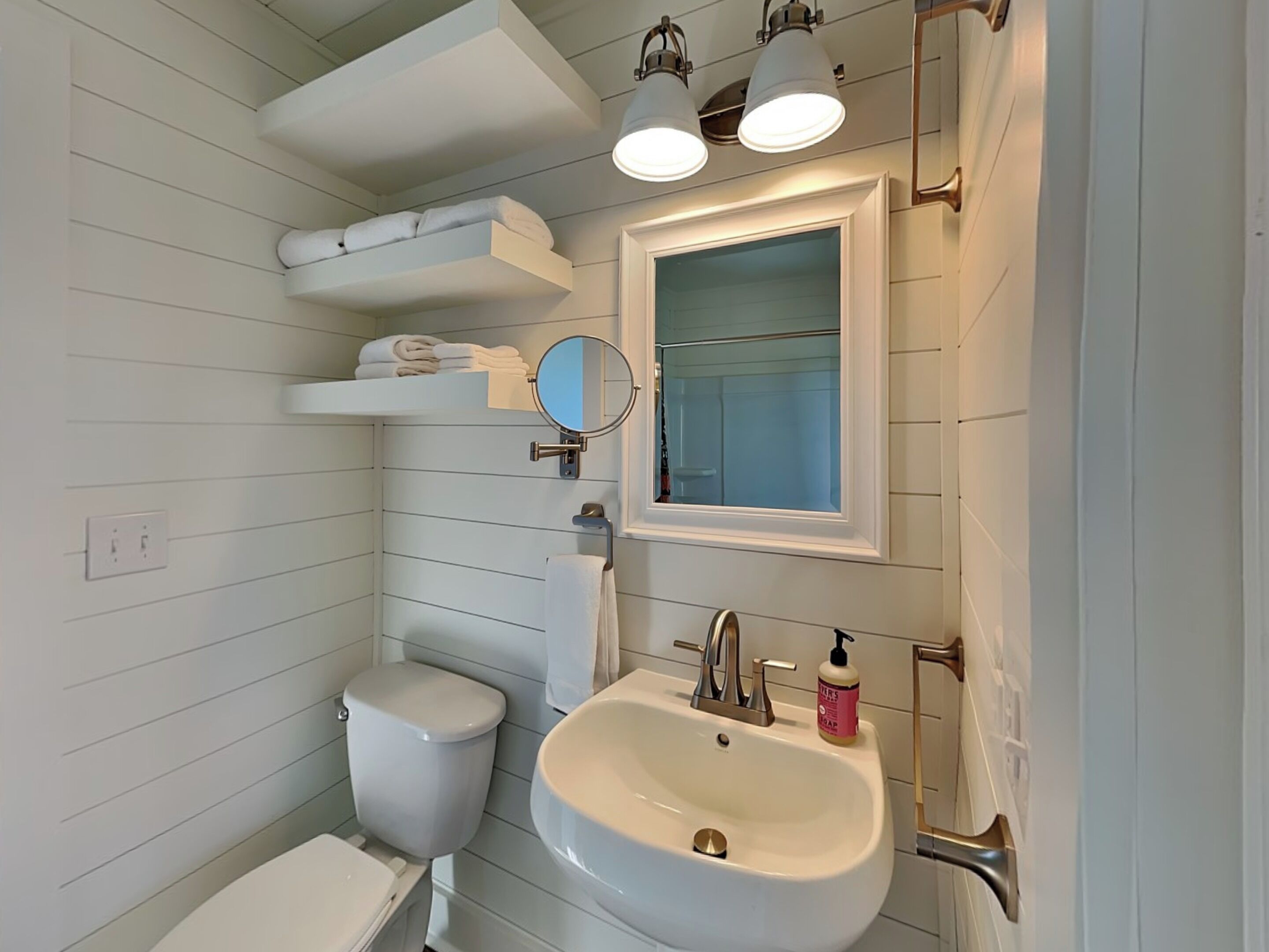A bathroom with a white sink, a toilet, a mirror, and a towel rack.
