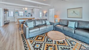 A modern living room with a grey leather sofa, a wooden coffee table, and a patterned rug.