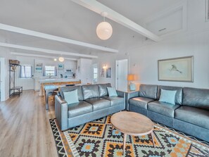 A modern living room with a grey leather sofa, a wooden coffee table, and a patterned rug. - Walking on Sunshine by Topsail Realty (Holly Ridge)
