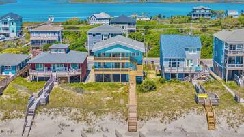 A coastal residential area with houses featuring balconies and decks, connected by wooden walkways.