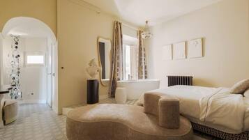 A bedroom with a bed, a vanity, a mirror, and a window with curtains.
