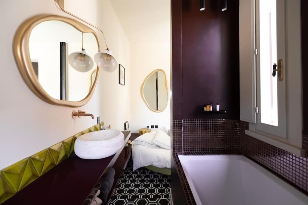 A bathroom with a round mirror, a white sink, and a bathtub.