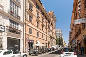 A street with parked cars and motorcycles, a restaurant with outdoor seating, and a building with a sign for a Mandarin restaurant. - Via Veneto Supreme Terrace (Rome)