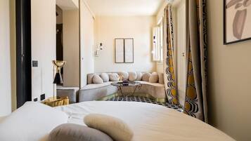 A hotel room with a bed, a sofa, a small table, and a decorative lamp.