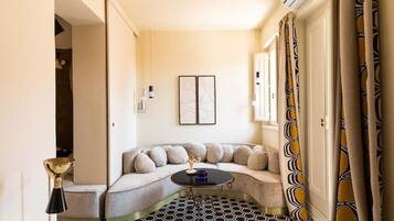A corner room with a curved sofa, a small round table, and patterned flooring.