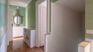 Un couloir doté d’un plancher en bois, d’une porte blanche et d’un miroir encadré d’un cadre orné.