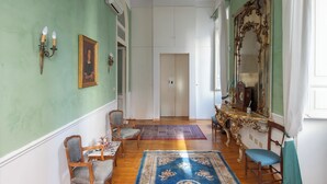 Un couloir avec un mur vert, un miroir et une porte au fond.