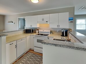 A modern kitchen with white cabinets, a microwave, stove, and a coffee maker. - The Sassy Sea Turtle by Topsail Realty (Holly Ridge)
