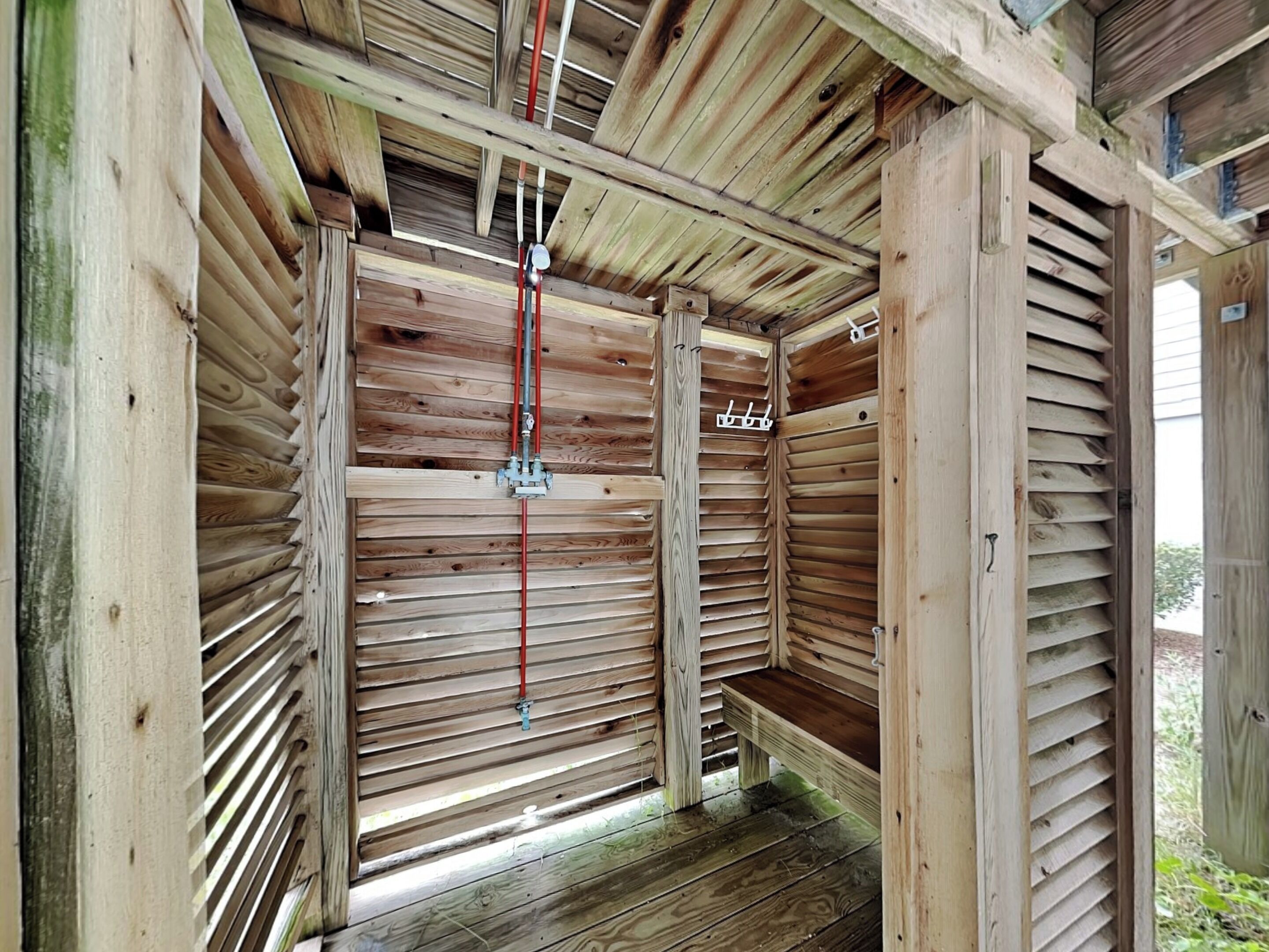 Une structure en bois dotée d’un toit à lattes et d’un élément central en métal.