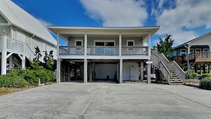 A two-story building with a balcony, a garage, and a staircase leading to an upper level. - The Sassy Sea Turtle by Topsail Realty (Holly Ridge)