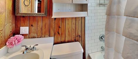 A bathroom with wooden paneling, a sink, toilet, and a bathtub.