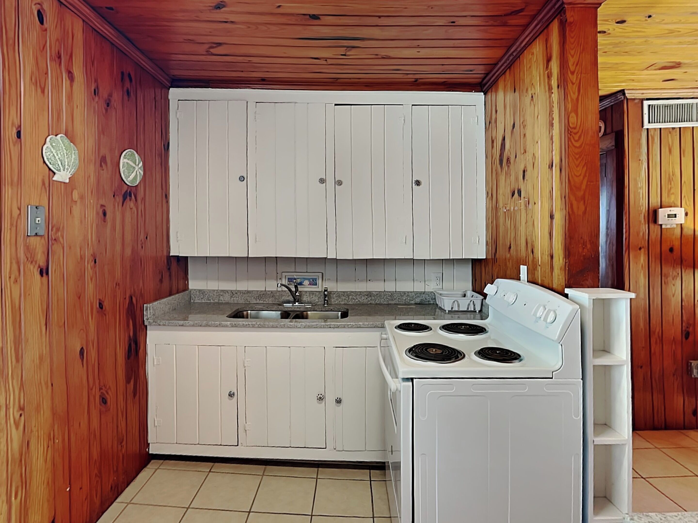 A compact kitchen with white cabinets, a sink, and a stove.