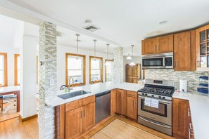Una cocina moderna con armarios de madera, electrodomésticos de acero inoxidable y encimera blanca.