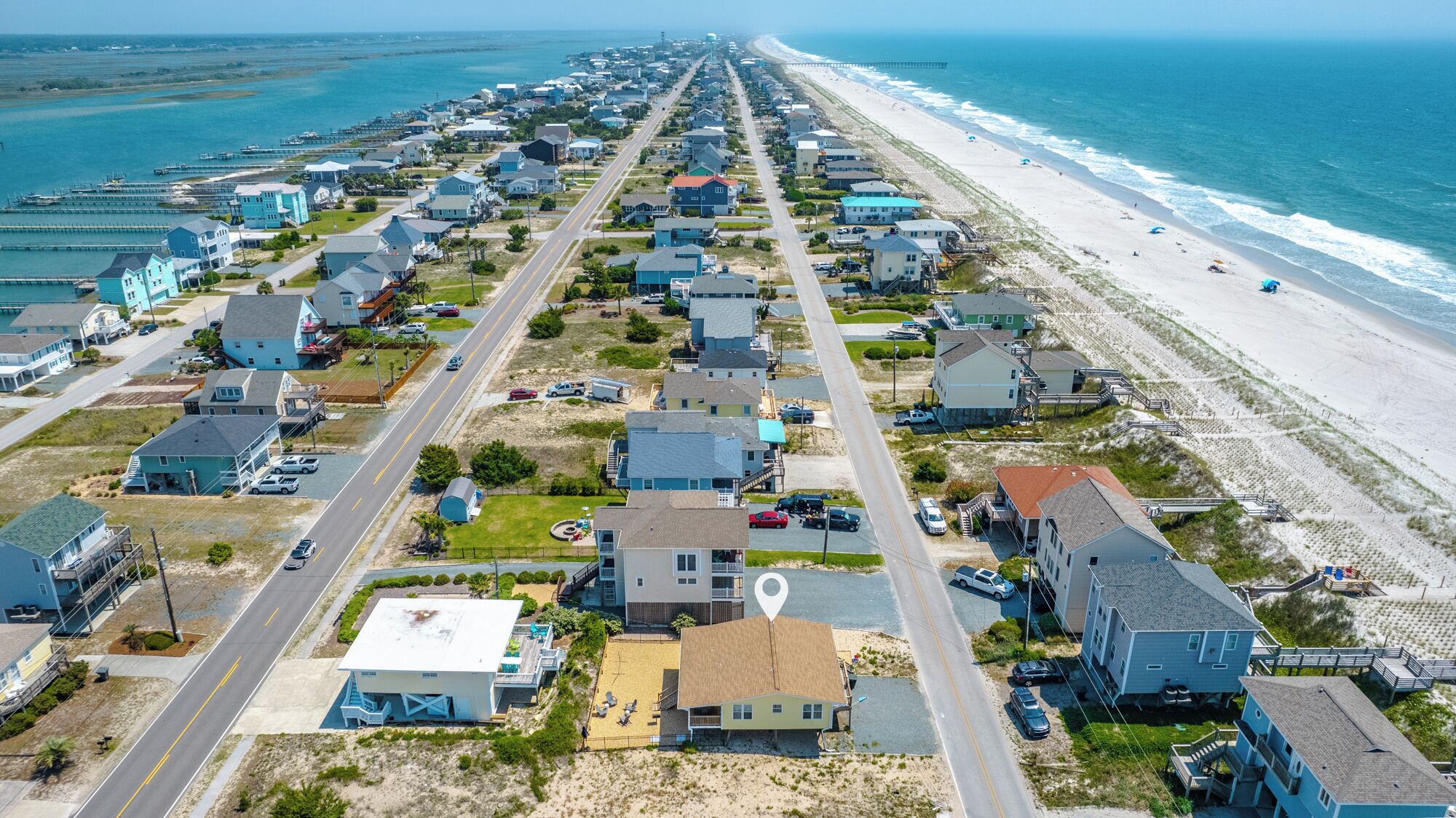 Zona residencial costera con casas, una playa y un muelle.