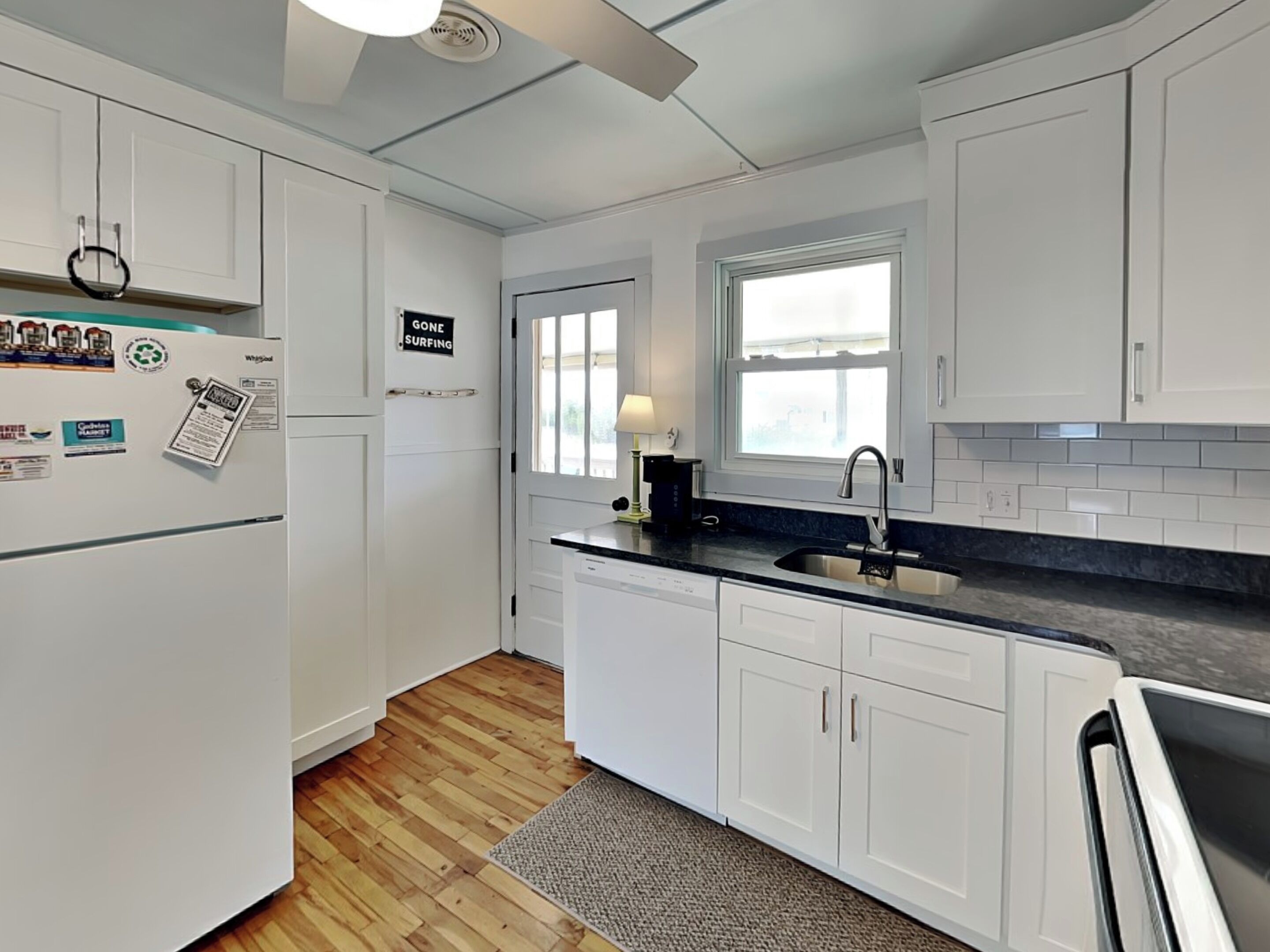 A modern kitchen with white cabinets, a black countertop, and a window above the sink.