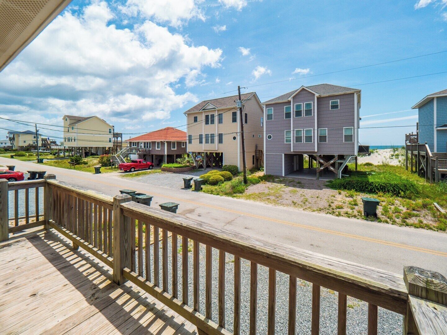 A coastal residential area with houses on stilts, a wooden deck, and a clear sky.