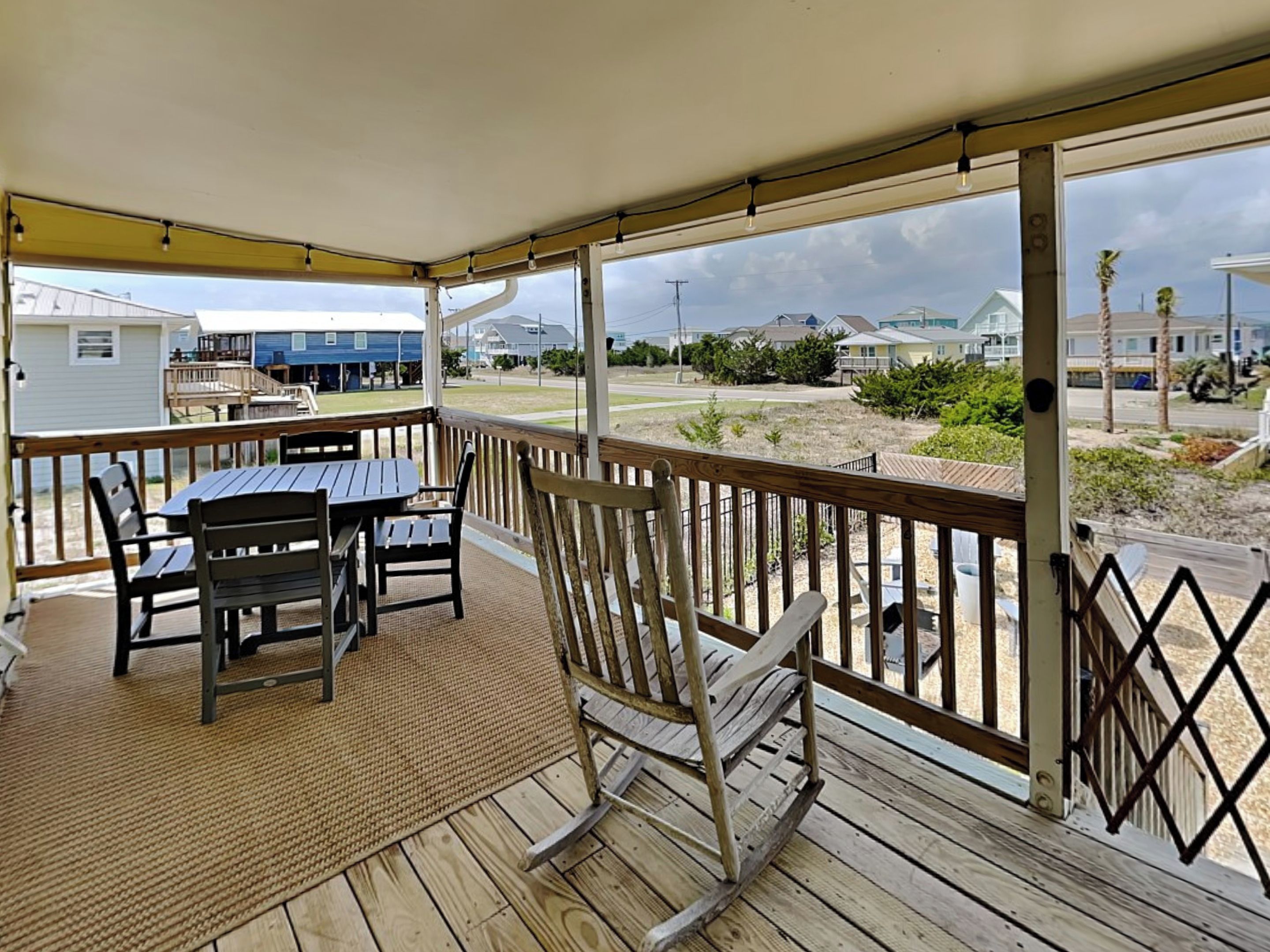 Un espace extérieur abrité, doté d’une terrasse en bois, d’une table avec des chaises et d’un fauteuil à bascule.