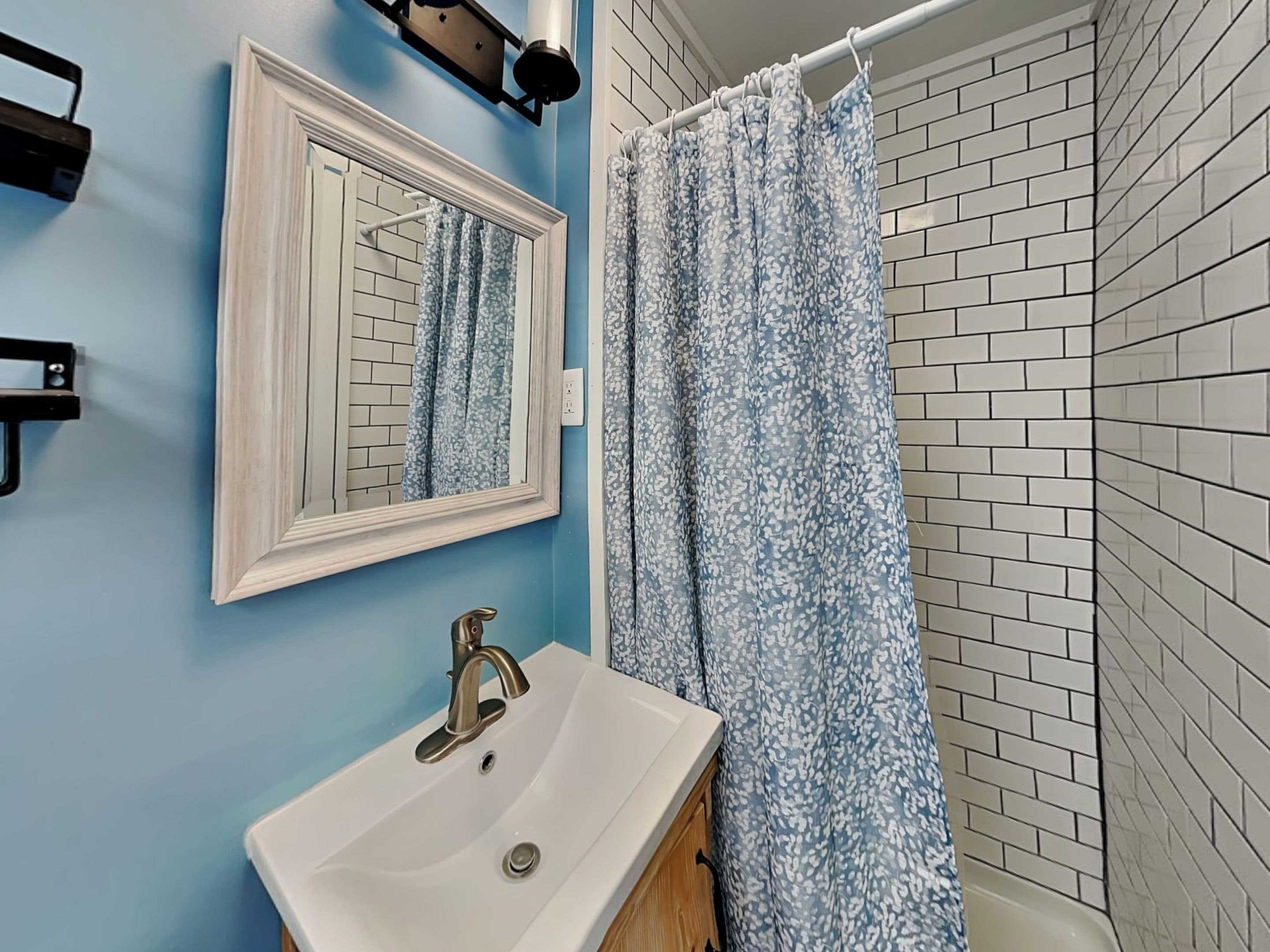 A bathroom with a white sink, a mirror, and a shower curtain with a floral pattern.