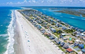 An aerial view of a coastal resort with rows of beachside villas, a sandy beach, and clear blue waters. - Mountains to Sea by Topsail Realty (Holly Ridge)
