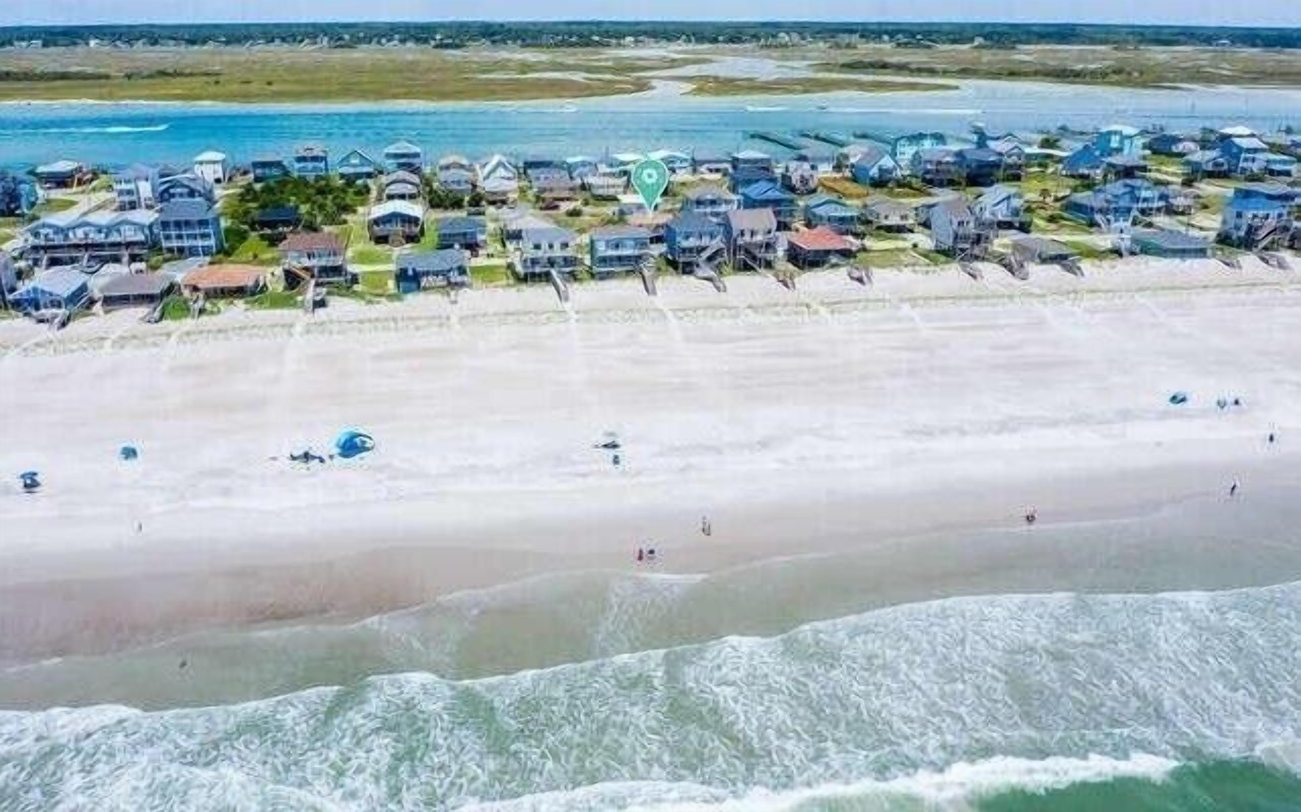 A coastal residential area with houses along the beach, some with ocean views.