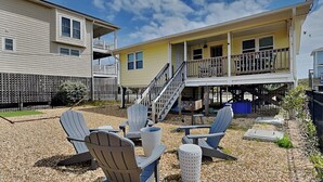 A patio area with Adirondack chairs, a small table, and a decorative urn. - Mountains to Sea by Topsail Realty (Holly Ridge)