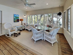 A sunlit room with wicker furniture, large windows, and a ceiling fan. - The Pack House by Topsail Realty (Holly Ridge)
