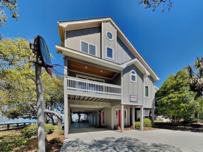 A two-story house with a balcony, a basketball hoop, and a sign indicating 'Packhouse'. - The Pack House by Topsail Realty (Holly Ridge)