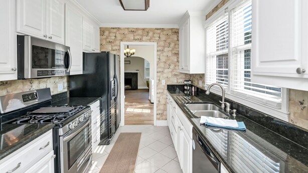 A modern kitchen with white cabinets, a black stove, and a black refrigerator. - Comfy West Columbia Get-Away (West Columbia)