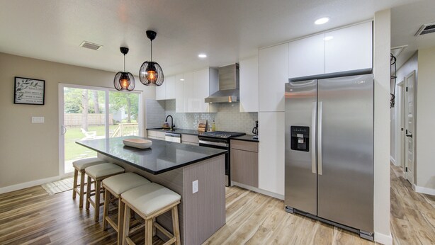 A modern kitchen with a central island, stainless steel appliances, and a view to the outdoors. - Coastal Getaway w/HotTub in La Marque! (La Marque)