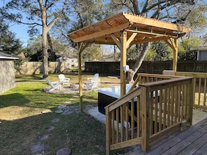Una terraza de madera con pérgola, mobiliario exterior y un jacuzzi.