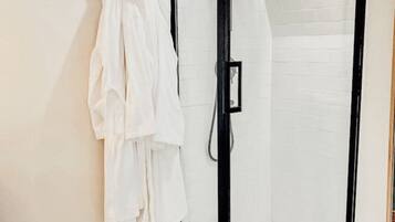 A modern bathroom with a glass-enclosed shower, white tiled walls, and a patterned floor.