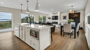 Een moderne keuken met een groot eiland, witte kasten en hanglampen.