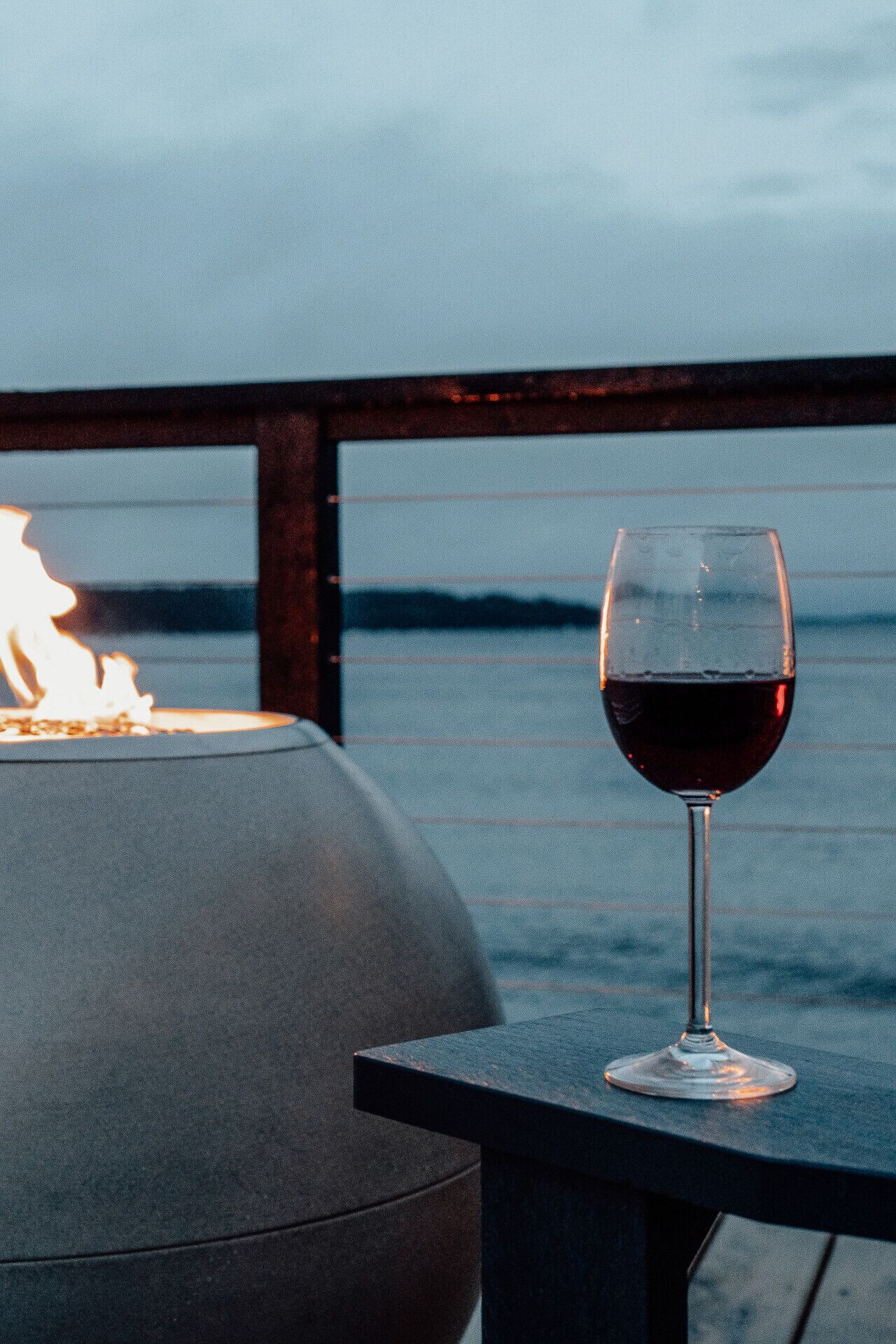 Una copa de vino tinto sobre una mesa con vistas al mar.
