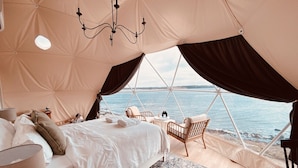 Eine Zelthütte mit Bett, Stühlen und Meerblick.
