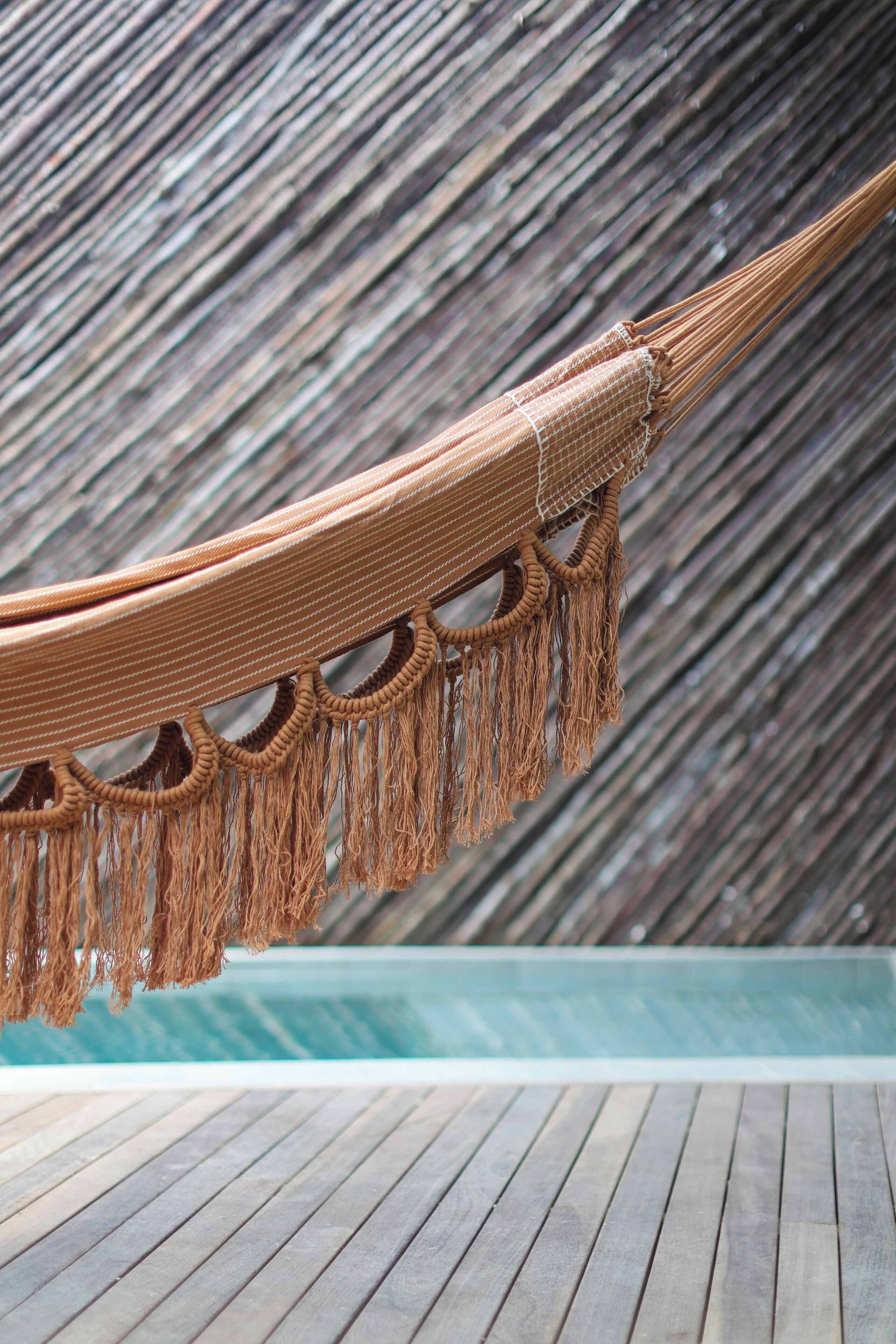 Un hamac agrémenté de détails en macramé et une terrasse en bois.