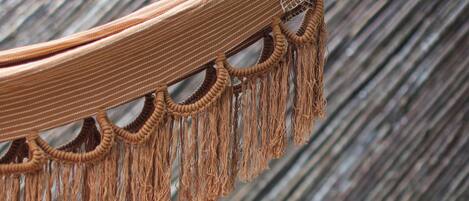 Un hamac agrémenté de détails en macramé et une terrasse en bois.
