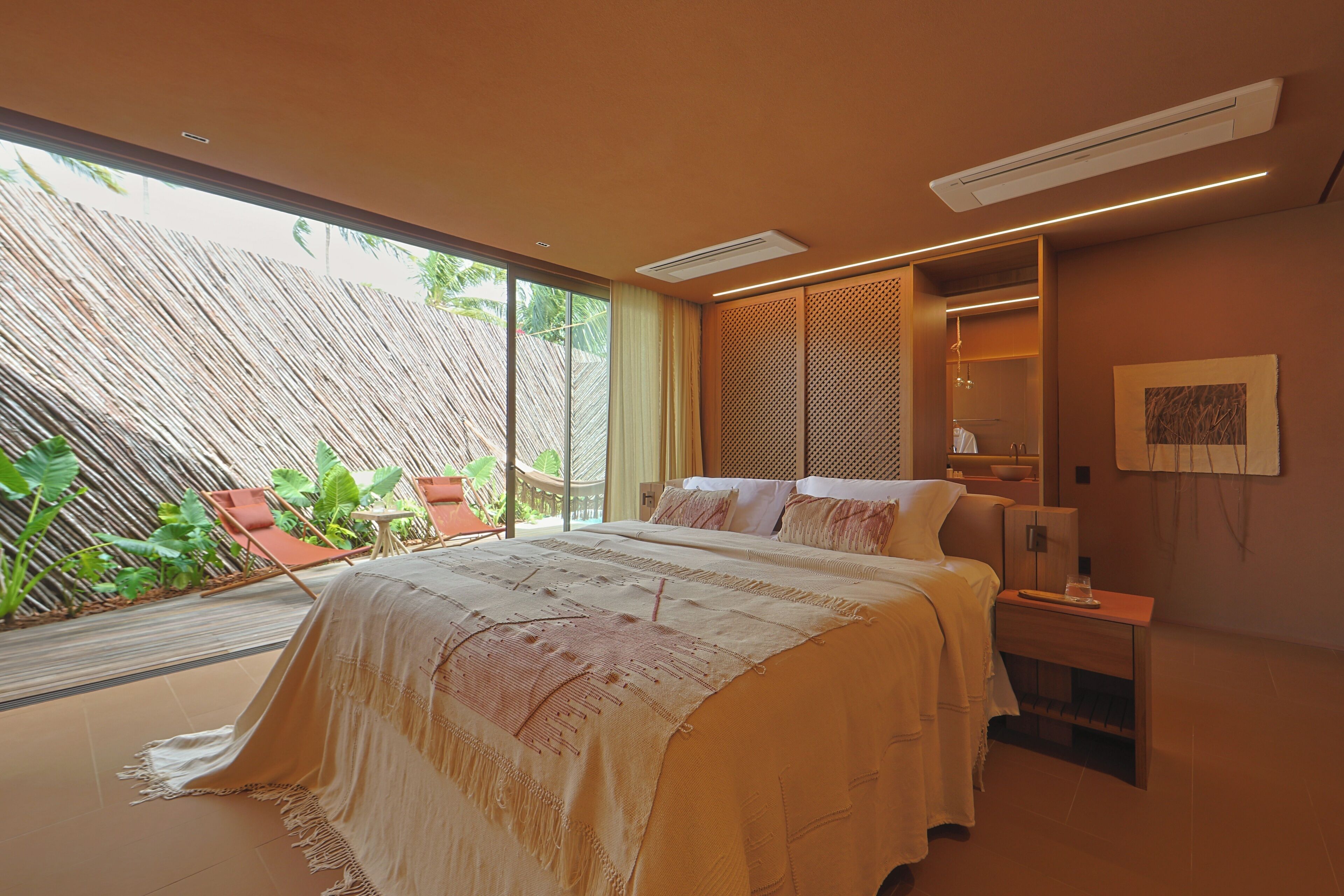A modern bedroom with a large bed, a bedside table, a nightstand, and a view of the outdoors.