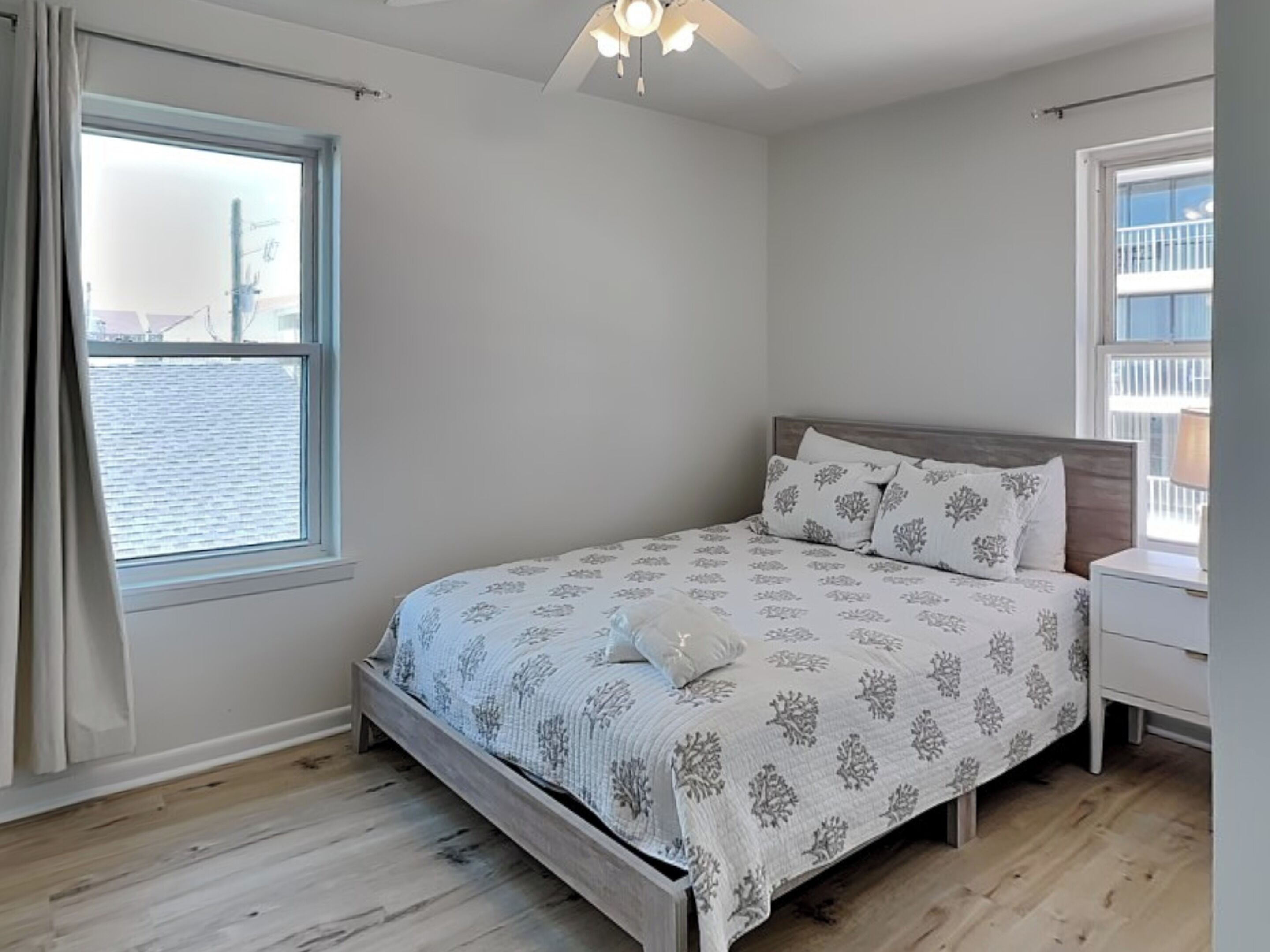 A bedroom with a bed, a nightstand, a window, and a ceiling fan.