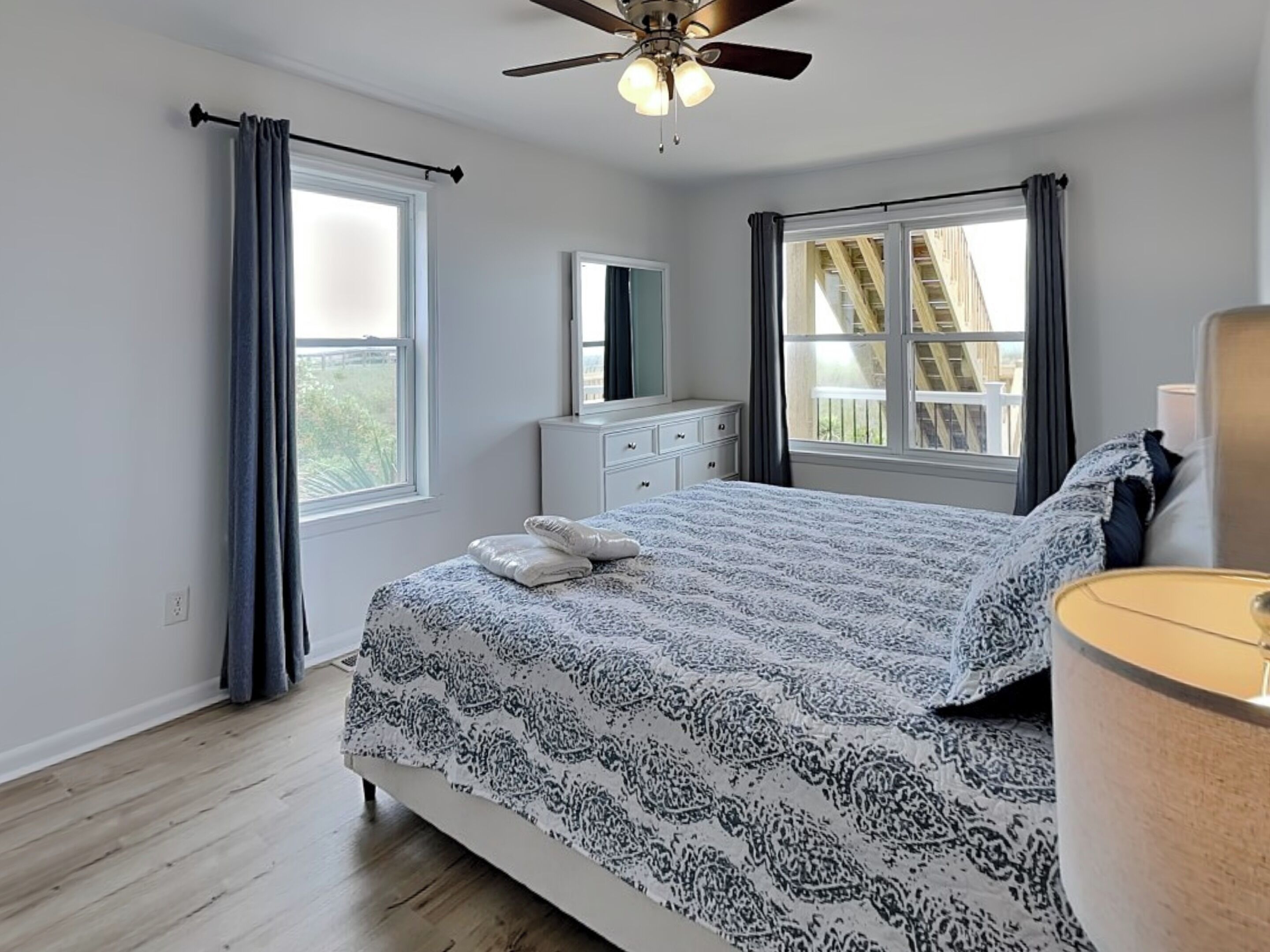 Une chambre à coucher avec un lit, une commode, un miroir et un ventilateur de plafond.