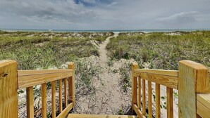 A wooden pathway leading to a beach with a clear sky. - Seaside Serenity by Carolina Retreats (Carolina Beach)