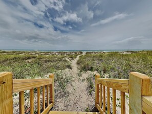A wooden pathway leading to a beach with a clear sky. - Seaside Serenity by Carolina Retreats (Carolina Beach)