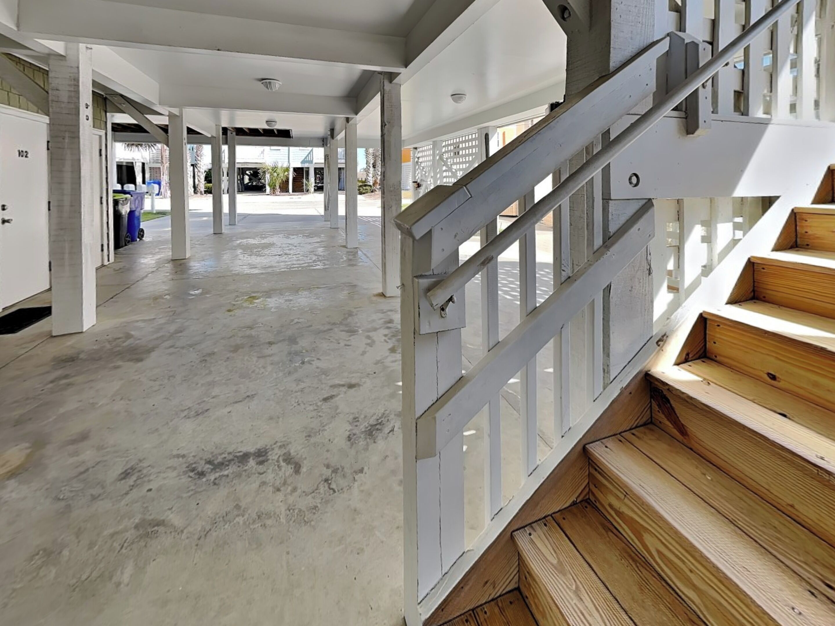 Un intérieur spacieux avec un plancher en béton, un escalier en bois et une vue sur l’extérieur.