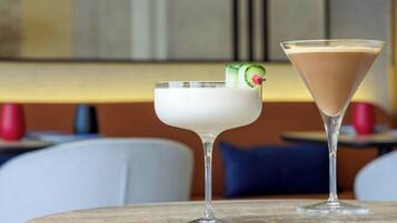 Two cocktails on a round table in a restaurant setting.