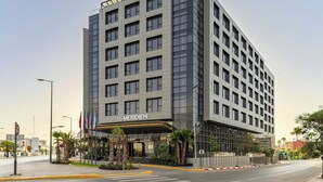 A modern hotel with a prominent 'Meridian' sign, featuring a symmetrical facade, multiple floors, and a well-maintained entrance area with palm trees and a small garden. - Le Méridien Casablanca (Casablanca)